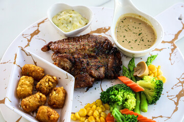 Grilled steaks and vegetables on marble plate isolated on white background.