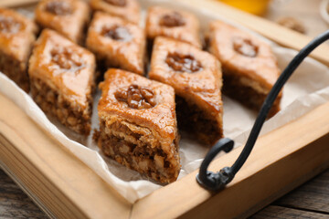 Delicious honey baklava with walnuts on wooden tray, closeup