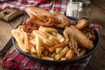 Baked chicken wings with french fries.