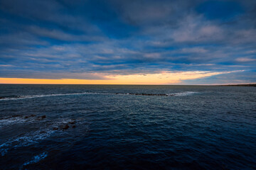 Sunset over the sea with cloudy sky and sun glow in the background