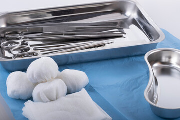 Medical equipment with dressing material in kidney-shaped tray.