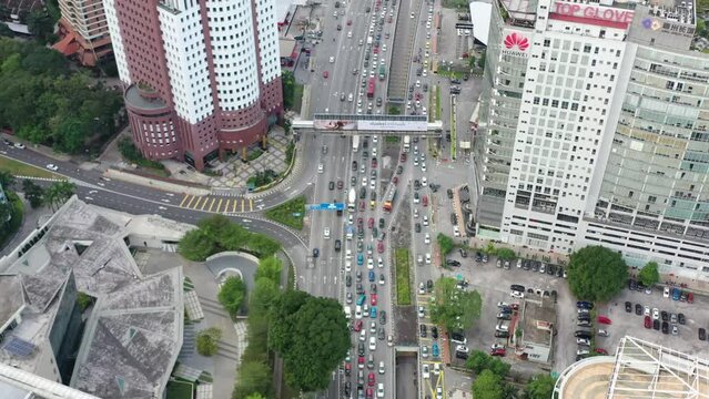 Birds eye view tilt up shot capturing the heavy traffics on busy jln tun razak surrounded by high rise corporate buildings and skyscrapers in downtown metropolitan area, kuala lumpur, malaysia.