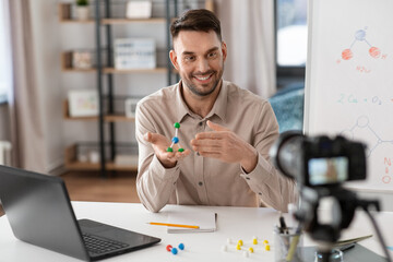 distance education, school and video blogging concept - happy smiling male chemistry teacher with camera and molecule model having online class at home office