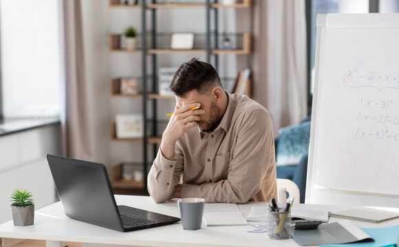 distance education, remote job and stress concept - tired male teacher with laptop computer working at home office - Powered by Adobe