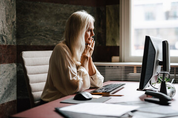 Female lawyer with long white hair staring at computer in office