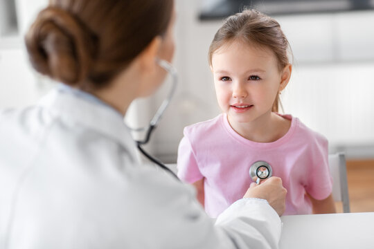 medicine, healthcare and pediatry concept - female doctor or pediatrician with stethoscope and little girl patient on medical exam at clinic