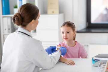 medicine, healthcare and vaccination concept - female doctor or pediatrician talking to little girl...