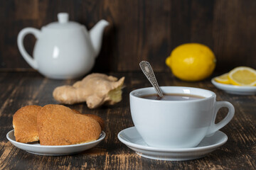 White cup of tea with lemon and ginger on wooden table