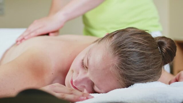 masseuse massages a woman back with öl