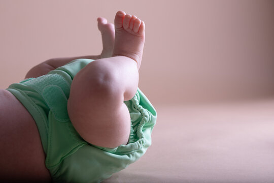 Baby's feet and green reusable diaper. Zero waste baby care concept.