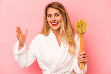 Young caucasian woman holding back scratcher isolated on pink background receiving a pleasant surprise, excited and raising hands.