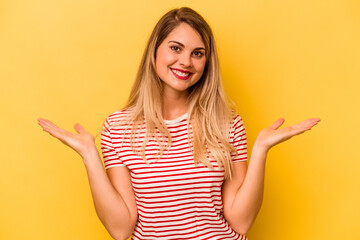 Young caucasian woman isolated on yellow background makes scale with arms, feels happy and confident.