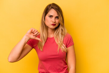 Young caucasian woman isolated on yellow background showing a dislike gesture, thumbs down. Disagreement concept.