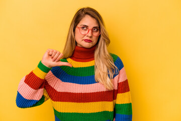 Young caucasian woman isolated on yellow background showing a dislike gesture, thumbs down....