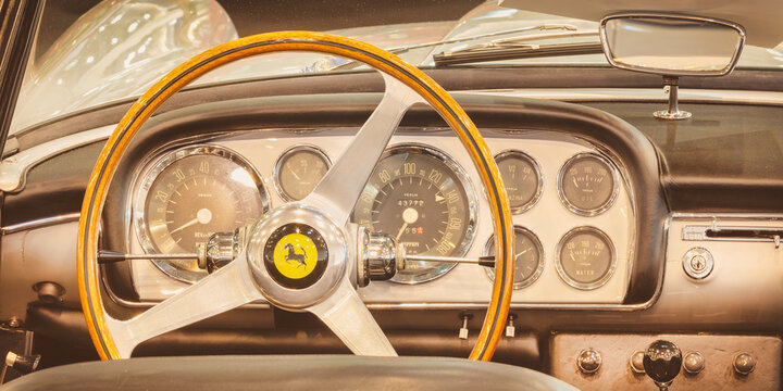 Retro styled image of the interior of a classic Ferrari sports car with wooden steering wheel in Essen, Germany on March 23, 2022