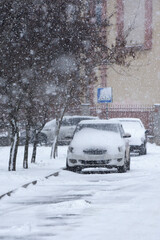 A very snowy day in winter. Snow falls on cars.