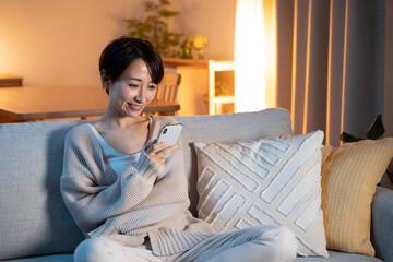 夜に家でリラックスする女性（スマホ・メール・インターネット）