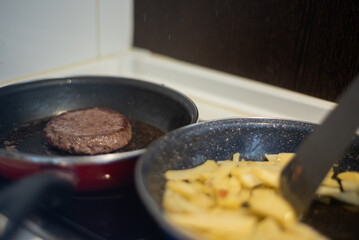 Cooking meat and fries in oily saucepan   