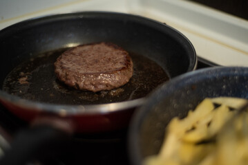 Cooking meat and fries in oily saucepan   