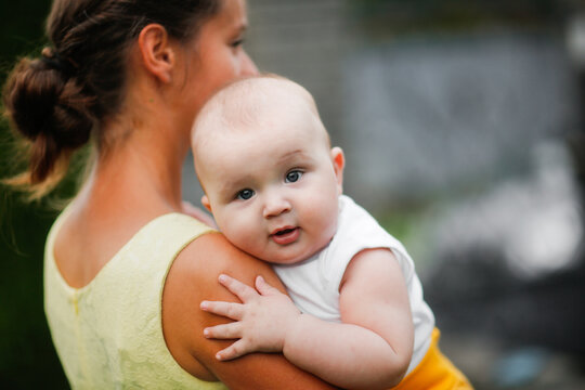 Cute bald chubby baby in the arms of mom in the summer