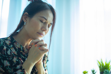 Close up of woman hands praying with laptop at home. Church services online concept.