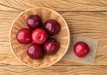 Plums in a basket over wooden table