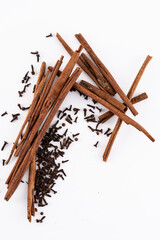 Cinnamon sticks and dried cloves on a white background.