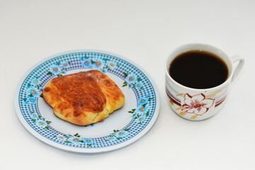 Breakfast -  porcelain platte  with croissant  and a cup of coffee  on black background