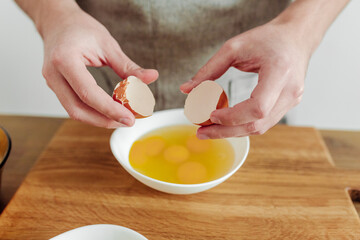 Man in apron cooking, in progress. Broken egg in hand