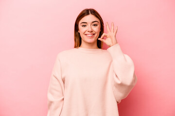 Young caucasian woman isolated on pink background cheerful and confident showing ok gesture.