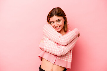 Young caucasian woman isolated on pink background hugs, smiling carefree and happy.