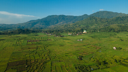 Aerial view of terraced rice fields, green farm fields in rural or rural areas of Lombok. Mountain hill valley at sunrise in Asia. Natural scenery background.