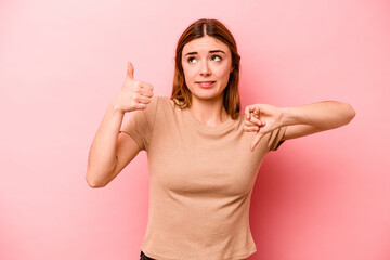 Young caucasian woman isolated on pink background showing thumbs up and thumbs down, difficult choose concept