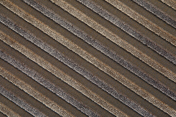 The texture of a natural beige cotton corduroy fabric with light stripes, located diagonally. The ridges of the corduroy on the diagonal