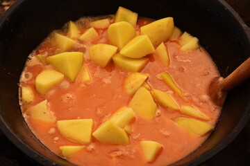 food cooking in stew pot ,tocana, ceaun,potatoes in orange sauce,soup