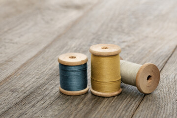 needlework and hobby concept, wooden spools of thread on an old table, sewing and tailor accessories