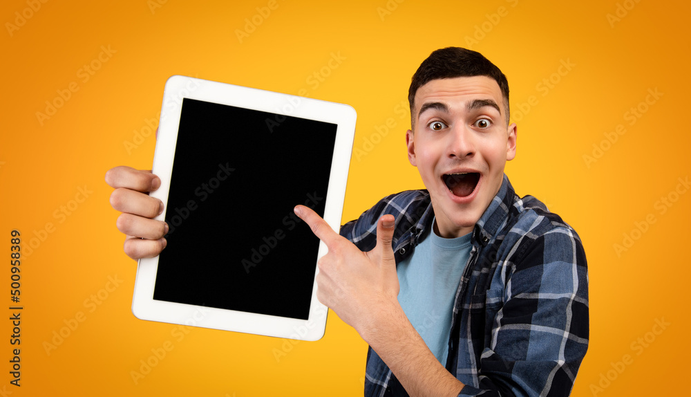 Poster excited hipster guy pointing at tablet with blank screen