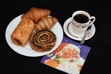 porcelain platter with Croissants, and a cup of coffee on black background