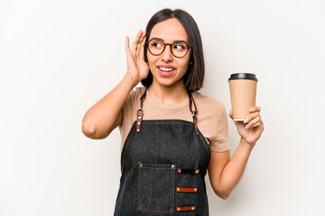 Young caucasian waitress woman holding take away coffee isolated on white background trying to listening a gossip.