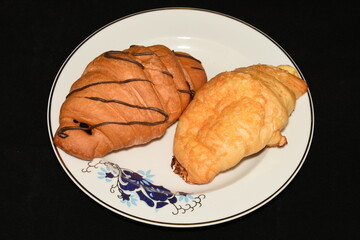 Breakfast.  porcelain platter  with Croissants, donuts. crullers  on red  background