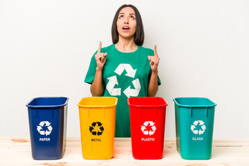 Young hispanic woman recycling isolated on white background pointing upside with opened mouth.