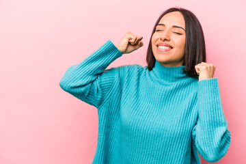 Young hispanic woman isolated on pink background raising fist after a victory, winner concept.