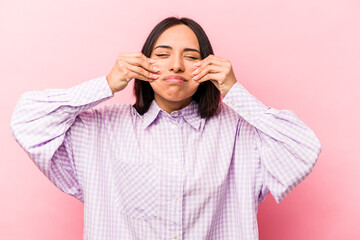Young hispanic woman isolated on pink background doubting between two options.