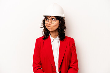 Young architect hispanic woman with helmet isolated on white background confused, feels doubtful and unsure.