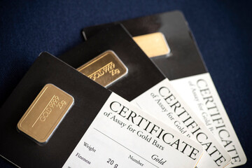 Several gold bars of different weights in a blister package with a certificate.  Selective focus.