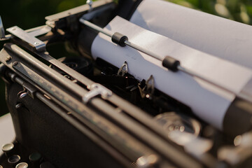 The end inscription on blank paper sheet loaded into a Retro typewriter. Dream writer's workplace in green wheat field. Inspiration, Creative freedom and remote work concept