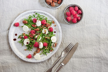 Summer salad with arugula, raspberries, mozzarella cheese and pecan nuts. Morning, breakfast, healthy food. Selective focus