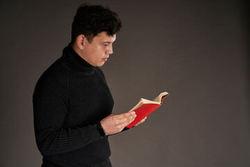 Latin man reading a red book, isolated on gray background
