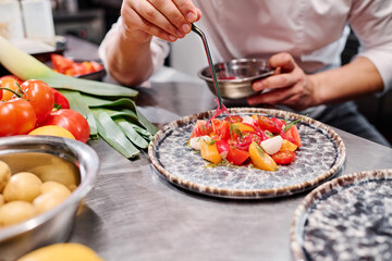 Close-up of chef decorating delicious dish on plate at table before serving