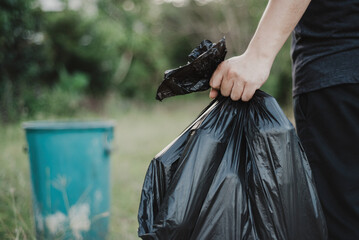 Hand holding a garbage bag ready to be taken to the waste disposal site.